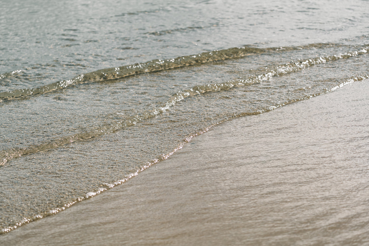 Gentle waves washing over wet sand at the shoreline